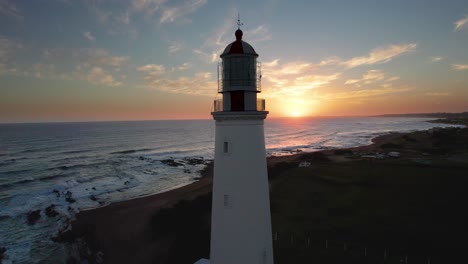 vista al atardecer del faro de farol en portugal con las olas del océano, fotografía aérea