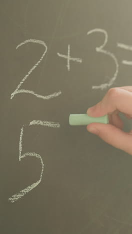 schoolgirl writes mathematical problems with chalk on blackboard slow motion. girl does task in mathematics lesson in elementary school. educational process