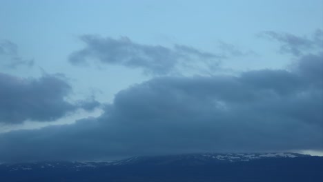 Timelapse-of-moving-clouds-in-mountains-with-snow,-at-dusk