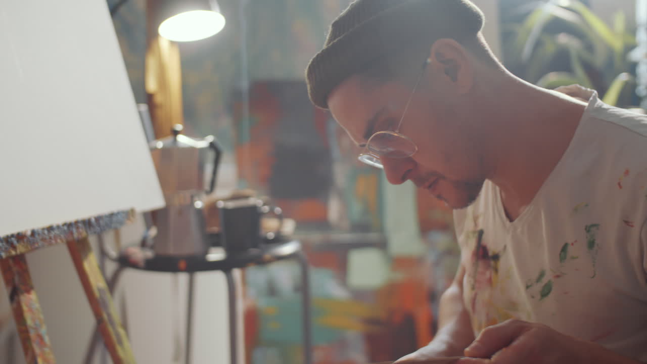 Man Mixing Paint on Palette before Painting in Studio