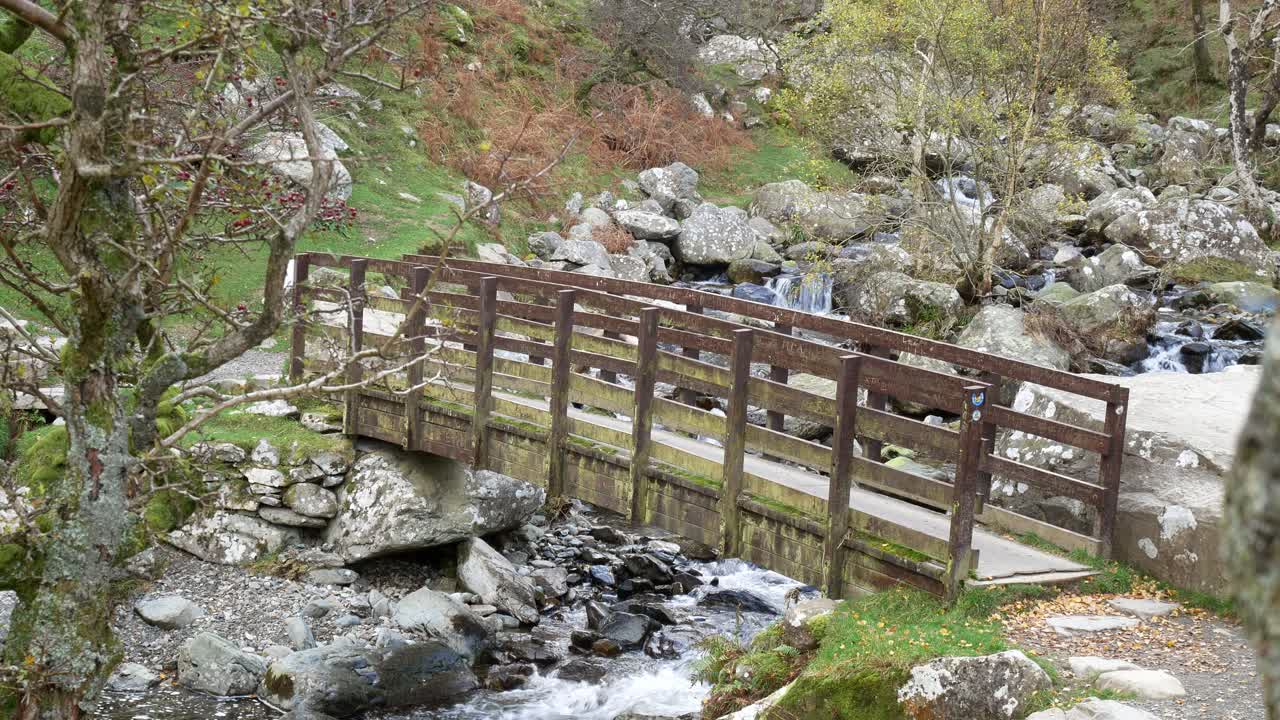 cascada de madera pasarela desnuda ramas de los árboles de otoño sobre río rocoso torrent empuje lento