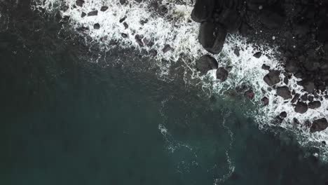 giant ocean waves smashing on the gray rocks below a rock cliff in isle of skye ocean scotland