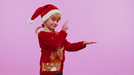 girl in red new year sweater deer showing thumbs up and pointing at on blank advertisement space