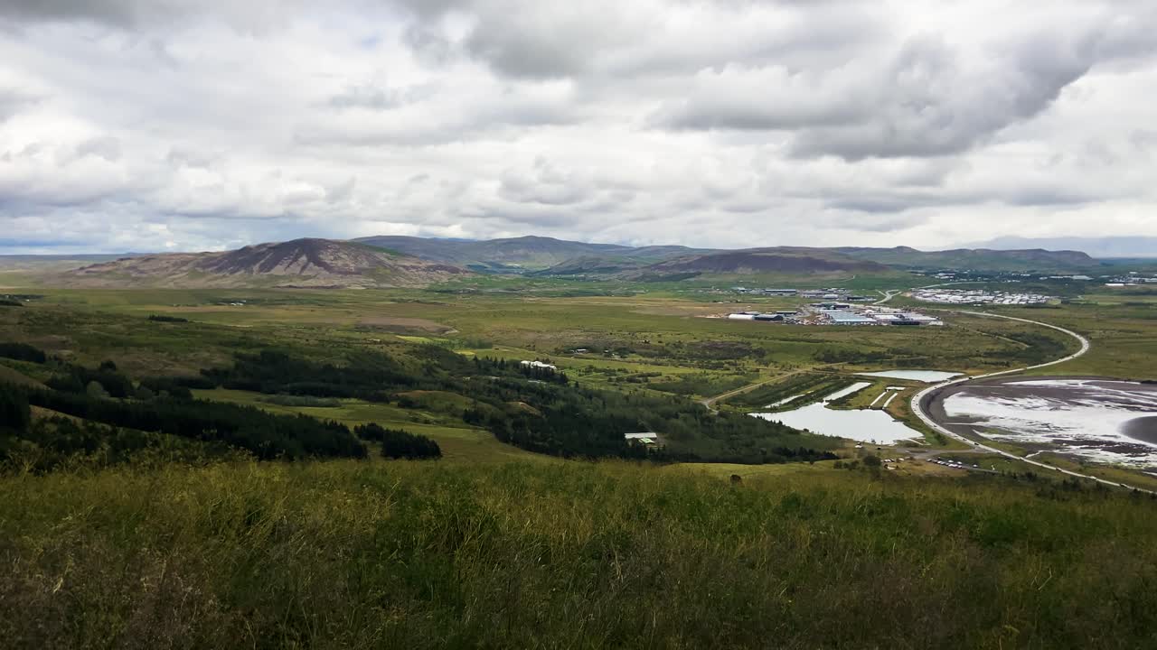 vista expansiva del paisaje islandés con montañas y cielos nublados, vegetación en primer plano