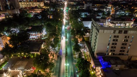 Fotografía-Aérea-Nocturna-De-Un-Vibrante-Bulevar-De-La-Ciudad,-Lleno-De-Vida-Con-El-Cálido-Resplandor-De-Las-Farolas-Que-Trazan-Un-Camino-A-Través-Del-Paisaje-Urbano.