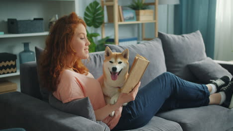 woman and dog relaxing on a couch, reading a book
