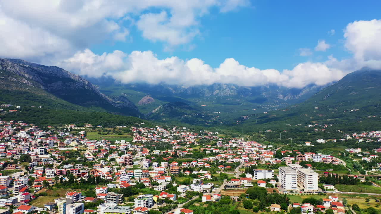 Flying above the panorama of Bar, Montenegro. Beautiful city view locating between the mountain range. Aerial perspective.