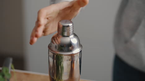 young male closing a cocktail mixer in slow motion in the kitchen at home
