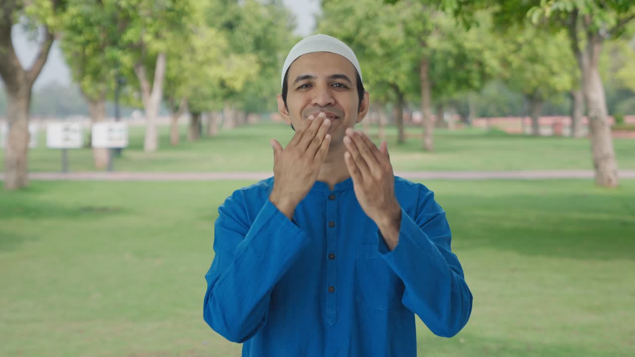 Parkta öpücükler gönderen mutlu Müslüman adam.