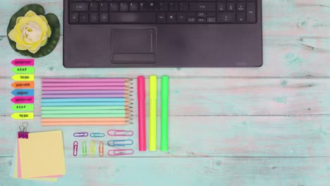 colorful office supplies and laptop appear on wooden table. colorful modern office work place. stop motion