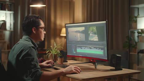 asian male video editor thinking while works with footage and sound on his personal computer, he works late at night