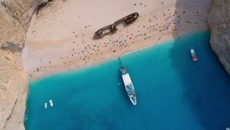 imágenes aéreas de arriba hacia abajo de los turistas que visitan la bahía del naufragio, la playa de navagio, zakynthos, grecia