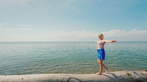 A-Focused-Woman-Walks-Along-A-Log-Maintains-Balance-With-Her-Hands