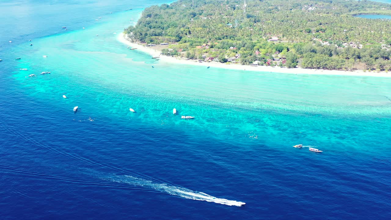 Caribbean Lush Island Surrounded By Light Blue Shallow Water And Deep Blue Water With Speed Boats Anchored In Beautiful Ocean - Speed Boat Dashing Fast In The Water - Aerial Shot