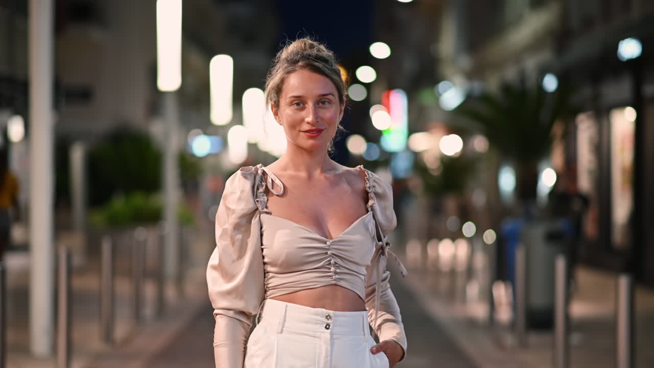 Caucasian woman walking and posing on a street in Cannes at night, illumination, France