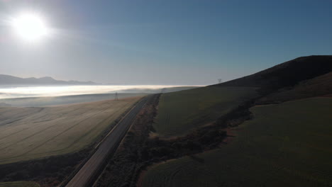 aerial view of misty plains and an empty road in the morning hours with mountains in the background