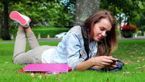 Estudiante-Feliz-Tumbada-En-El-Césped-Y-Contestando-Su-Teléfono