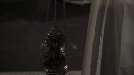 Close-up-of-Catholic-Christian-devotee-checking-the-incense-inside-the-burner-and-then-swinging-it-to-spread-the-smoke