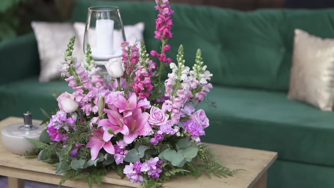Stilig blomsteroppsats til bryllup arrangert på trebord i koselig interiør
