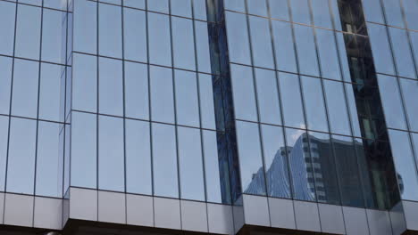 glass windows on city tower or skyscraper. blue colored glass with building reflection. office or luxury residential area. tall building in downtown financial district. expensive real estate
