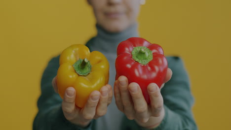Woman holding yellow and red bell peppers