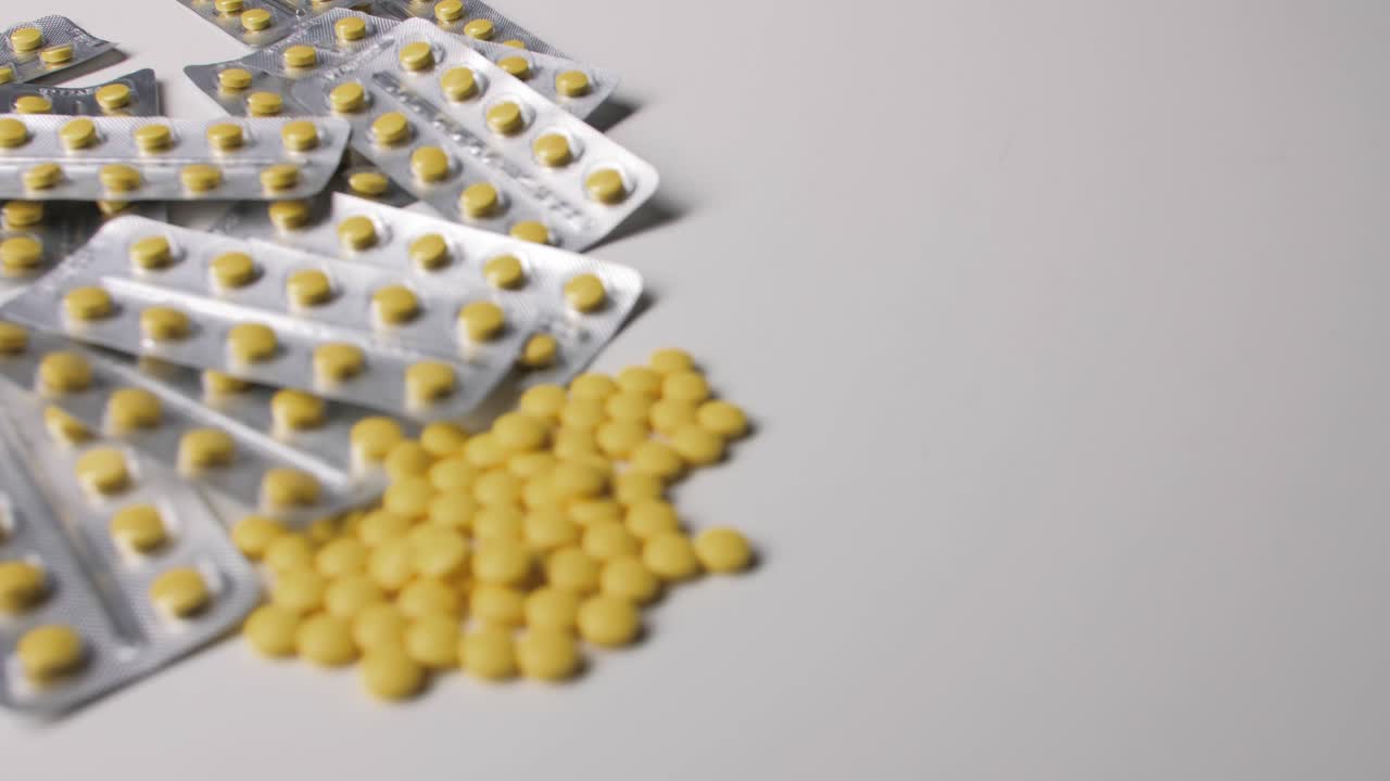 Yellow pills with packages on white background