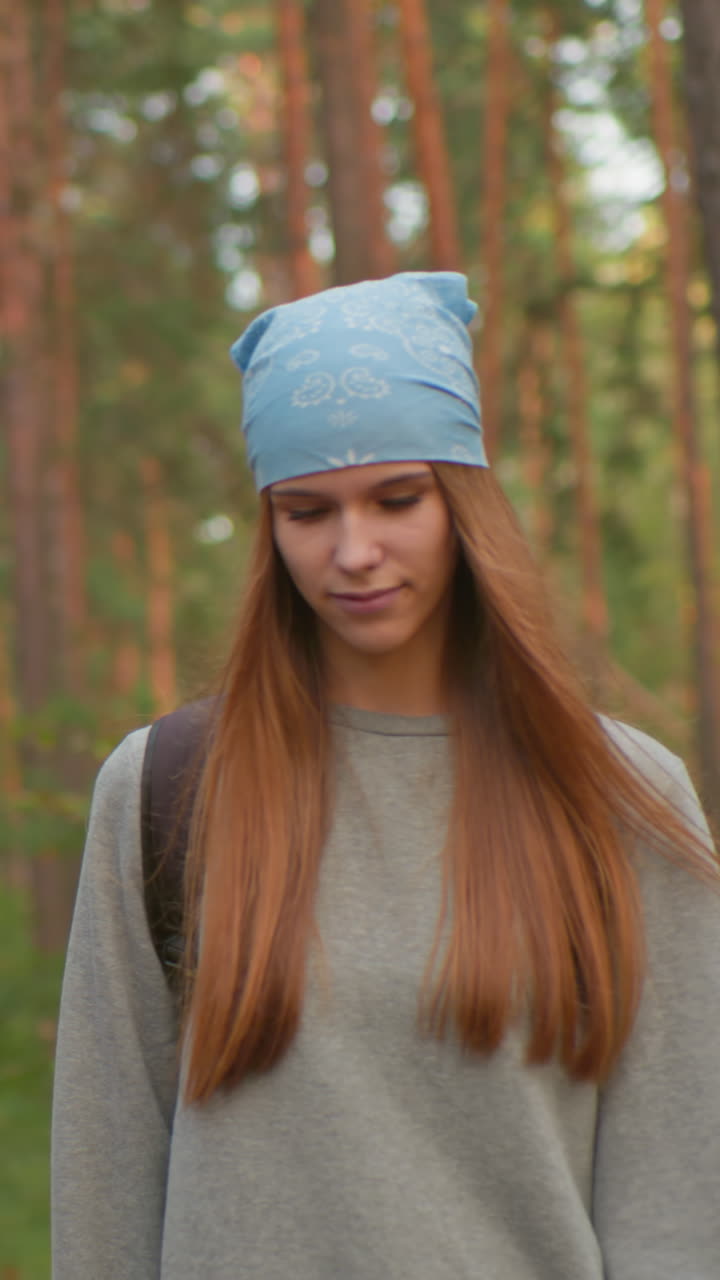 두 산책객이 조용한 숲에서 여행을 멈추고, 한 명은 파란색 밴다나를 입고 다른 한 명은 초록색 셔츠를 입고, 둘 다 사려 깊고 평화롭게 보이며, 울창한 초록색과 높은 나무로 둘러싸여 있습니다.