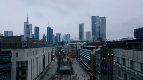 Forwards-fly-around-shopping-galleries-along-Zeil-street-in-city-centre.-Revealing-cityscape-with-downtown-skyscrapers-at-dusk.-Frankfurt-am-Main,-Germany