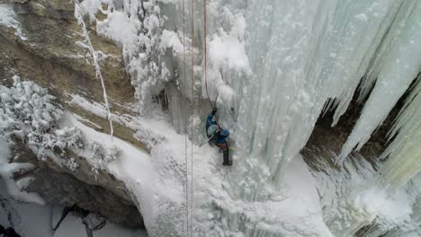 ice climber climbing frozen cliff during winter 4k