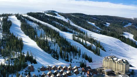 winter drone shot above big sky, montana reveals ski resort views, snow-draped trees, and cozy rental condos tucked into the mountainside, perfect for a scenic alpine vacation retreat