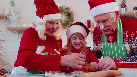 abuela, abuelo, nieta preparando y cocinando galletas de navidad caseras