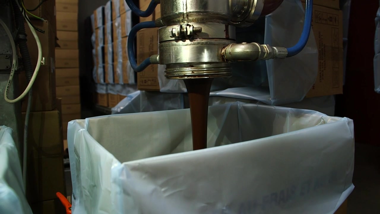 Produzione di cioccolato. Pompa che riempie un grande secchio di cioccolato