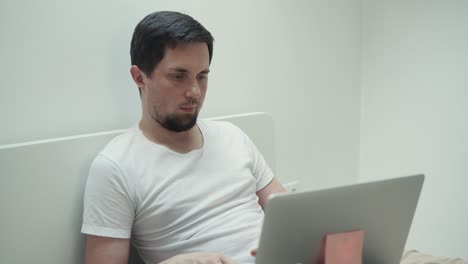 hombre trabajando en la computadora portátil en la cama