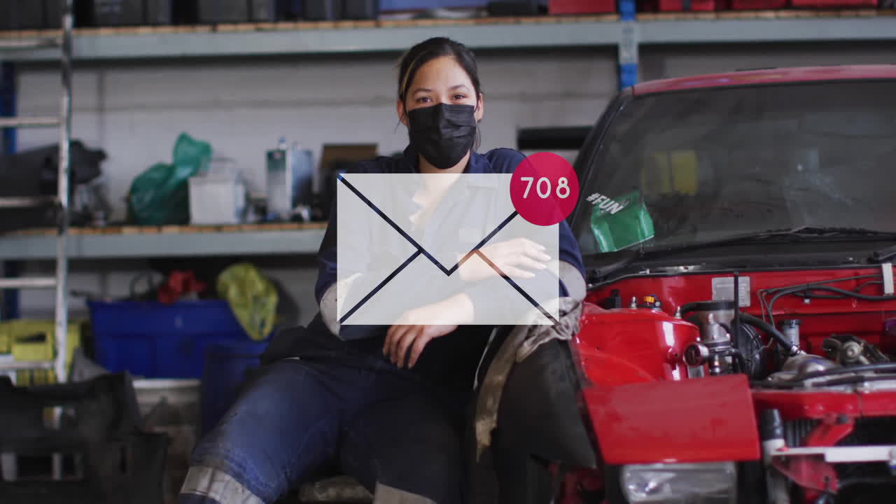 Ricezione di una notifica email, con un meccanico seduto accanto a un'auto in un'officina