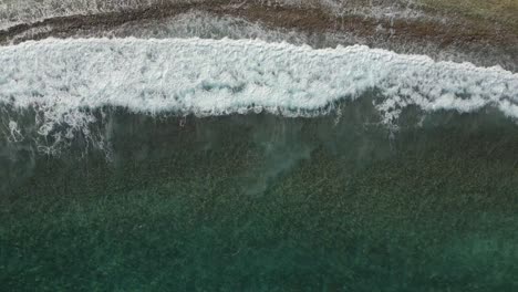 aerial view ocean waves from above with golf carts in the road