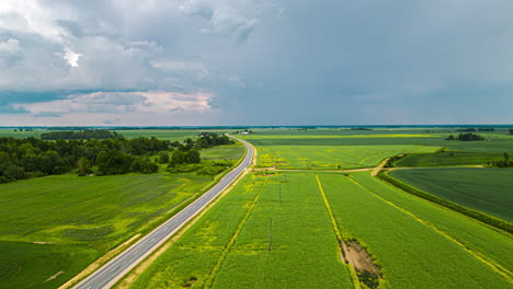 Gewitterwolken-Ziehen-über-Einer-Landstraße-Und-Ackerfeldern-Auf---Pullback-Luftbild-Hyperlapse