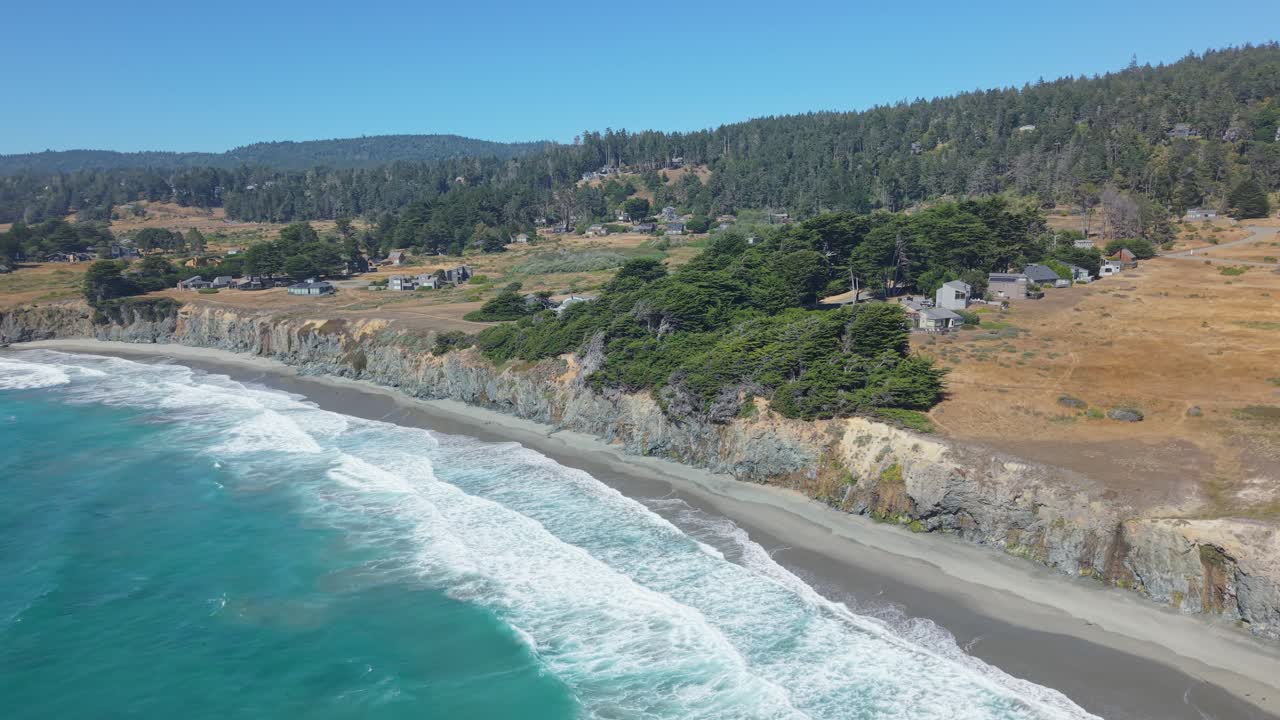 Sweeping aerial footage captures Black Point Beach’s rugged shoreline, where rolling surf meets dark sand under the golden light of a calm California afternoon