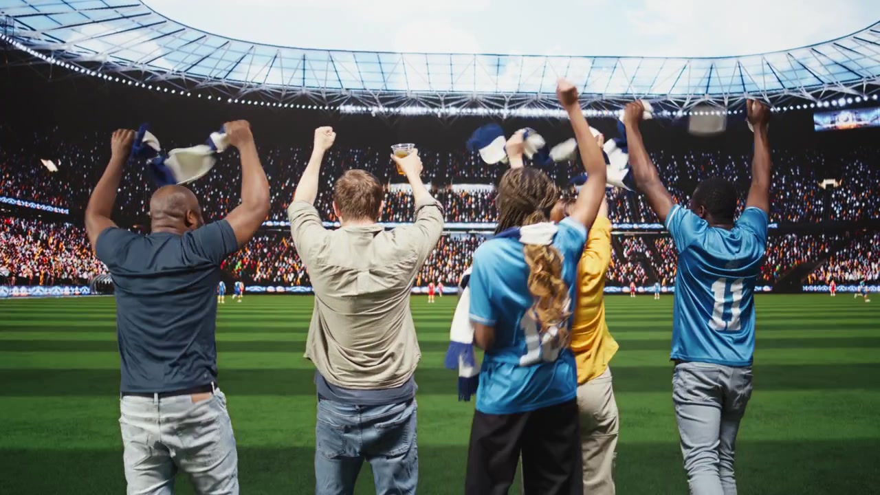 Aficionados al fútbol ven un partido en casa desde el sofá con tecnología de TV inmersiva.