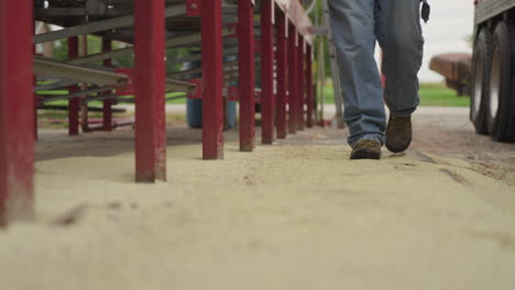 farmer walking on grain by a bin site on a farm field, low angle slow motion