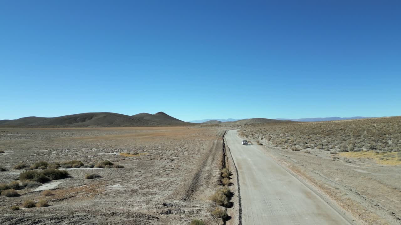drone filmado siguiendo un coche que viaja en el salvaje terreno montañoso de los andes, carretera en un paisaje desierto, cafayate, argentina