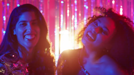 portrait of two women friends having fun dancing in nightclub bar or disco with sparkling lights 3