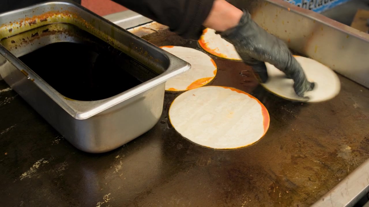 Rekaman makanan Meksiko yang menunjukkan proses memasak tortilla birria untuk taco quesabirria di atas panggangan datar selama persiapan dan penyajian taco quesabirria otentik