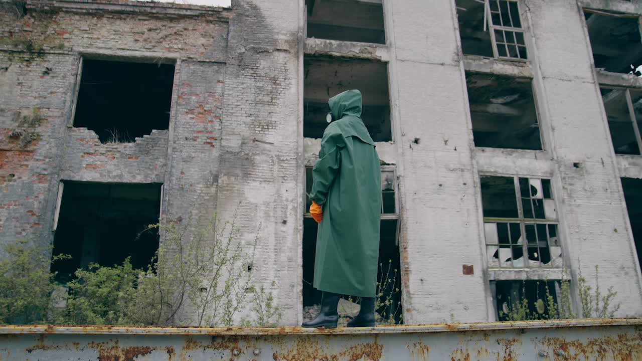 Man in special radioactive uniform walking down. Man wearing green chemical suit and gas mask.