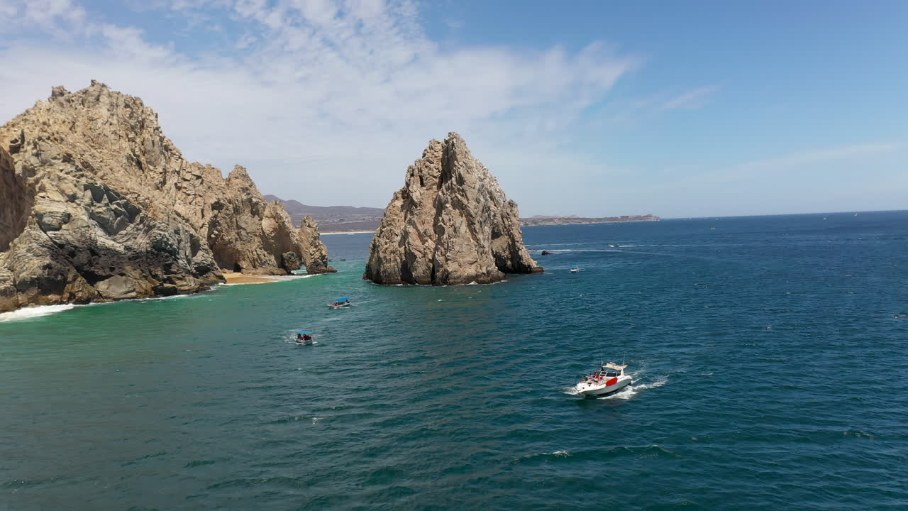 toma aérea de barcos en el océano con acantilados al fondo en cabo san lucas méxico