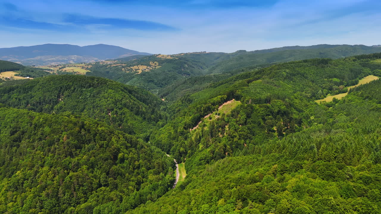 Vast green hills under a clear blue sky. Lush green hills stretch across the landscape, showcasing serene valleys and distant mountains on a sunny day