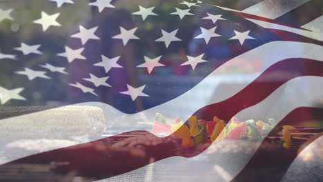 un grupo de amigos haciendo un picnic y una bandera estadounidense para el 4 de julio.