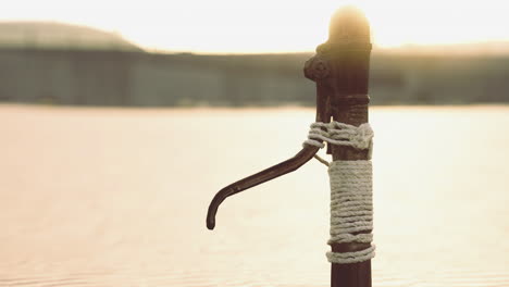 old water pump stands by the waters edge during sunset glow