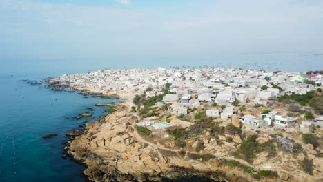 casas blancas aéreas y superpobladas junto a la costa de una isla rural.