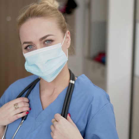 porträt der jungen ärztin im blauen mantel der medizinischen maske und im stethoskop