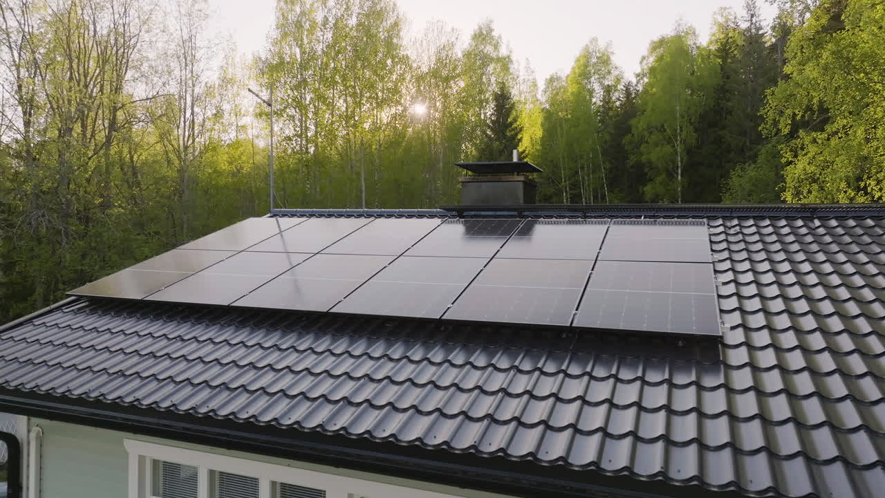 Aerial tracking shot of solar cells on a house roof, summer sunset in the Nordics